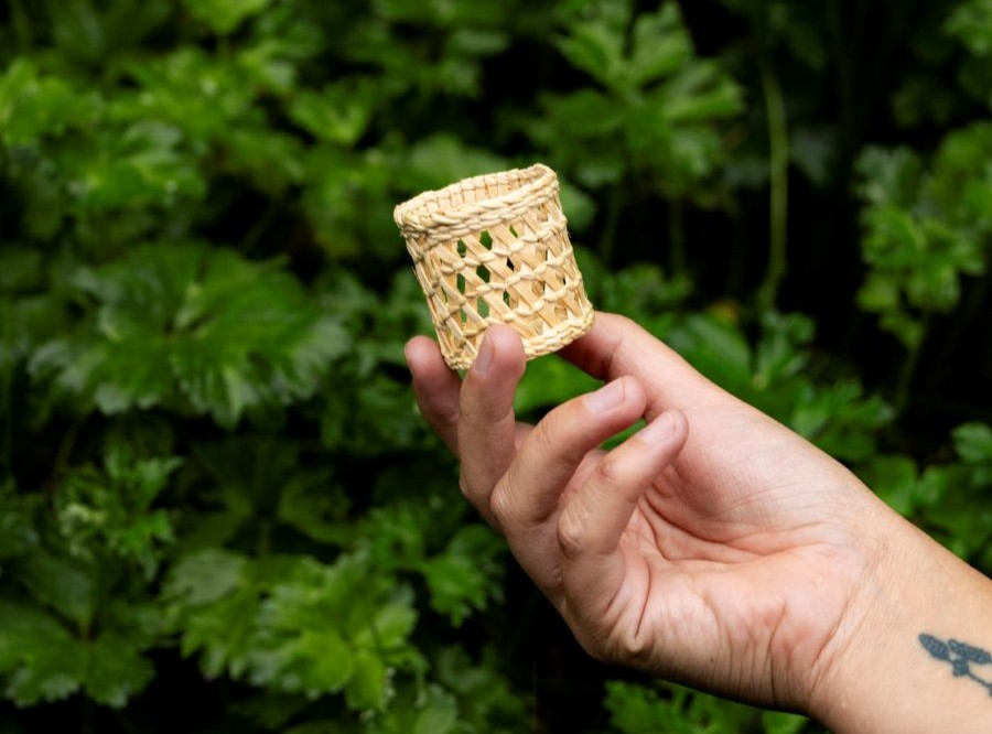 A close up shot of a small spruce root basket in a clam basket style.